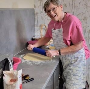 Frau Mayer rollt heiter den Teig für den Zwetschgenkuchen aus Frau Mayer rollt heiter den Teig für den Zwetschgenkuchen aus